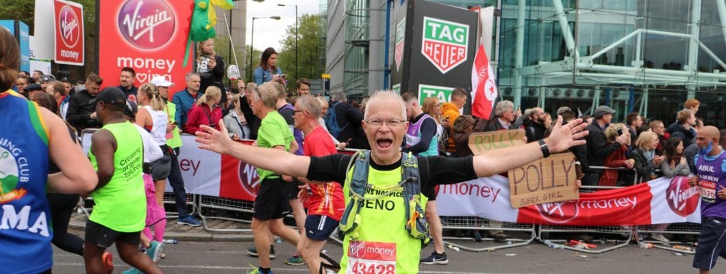 Man in yellow running vest with running number on it. Arms spread open waving.