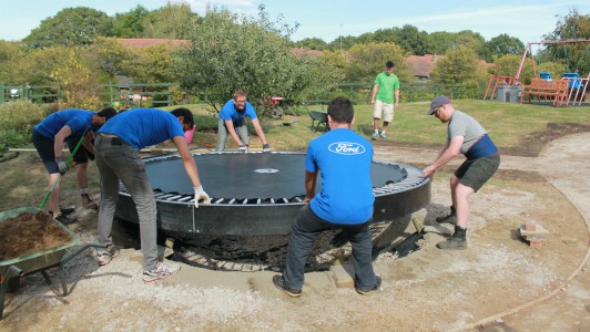 corporate volunteers installing a trampoline in the Little Havens gardens