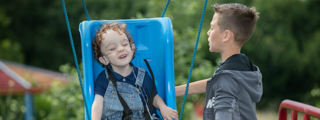 Little Havens child Miller being pushed on the swings by his older brother