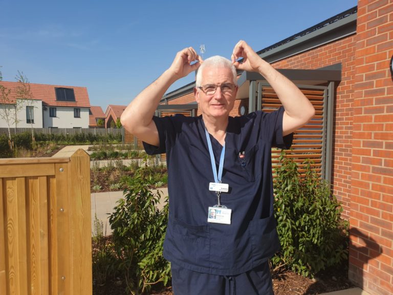 Dr Grahame outside the hospice pointing to his hair