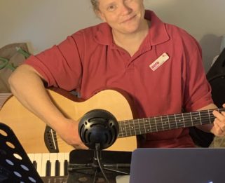 Ruth the music therapist set up at home with her guitar and microphone