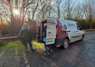 Two volunteers loading a christmas tree into the back of a van