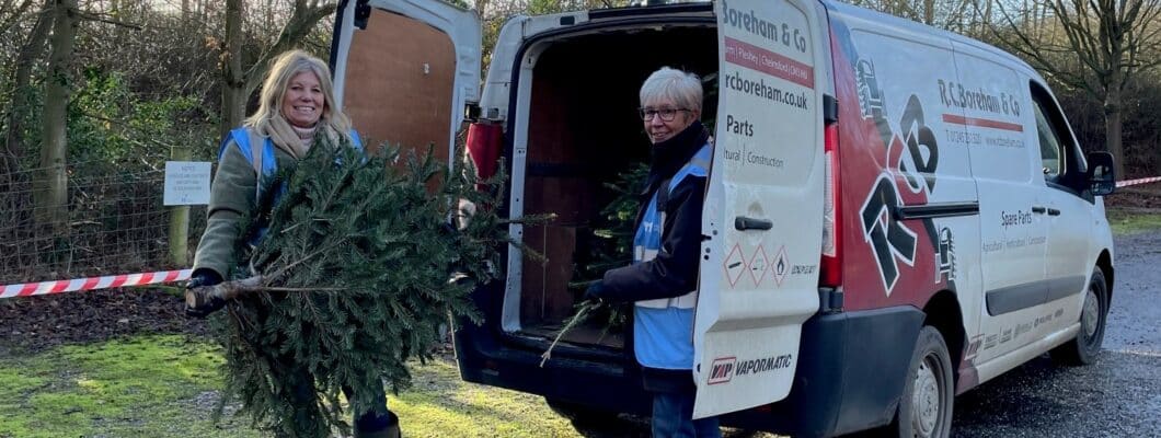 two volunteers loading a Christmas tree into a van