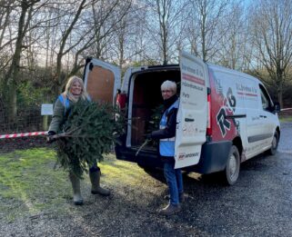 two volunteers loading a Christmas tree into a van