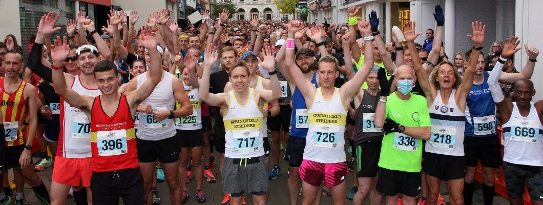 Chelmsford Marathon runners raising their arms in the air for a photo at the start line