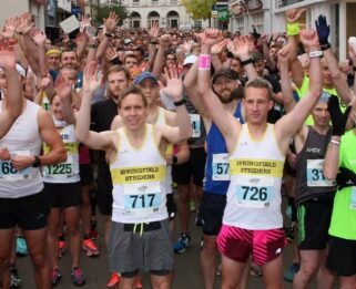 Chelmsford Marathon runners raising their arms in the air for a photo at the start line