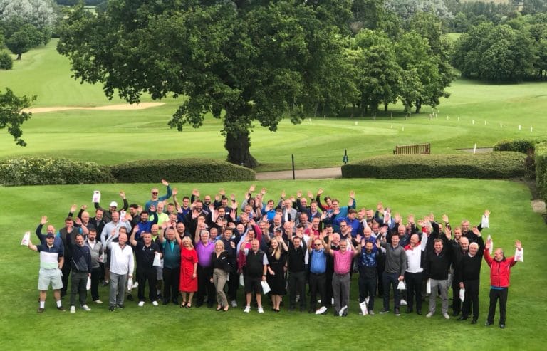 Group of golfers on the green waving at the camera