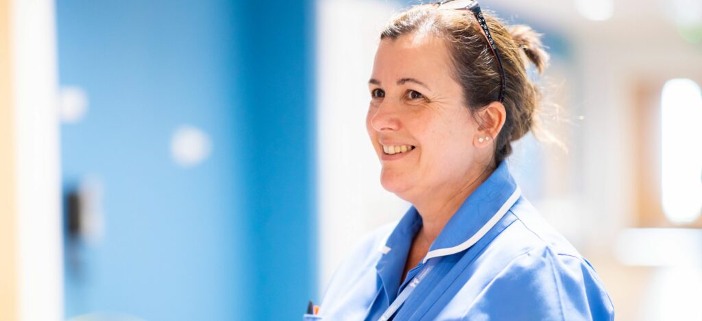 Karen nurse holding folder smiling in corridor