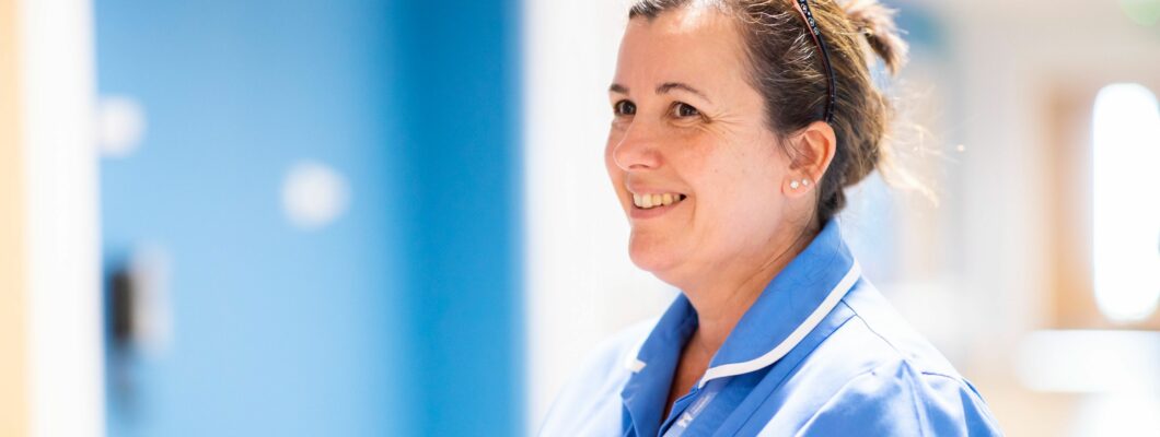 Karen nurse holding folder smiling in corridor