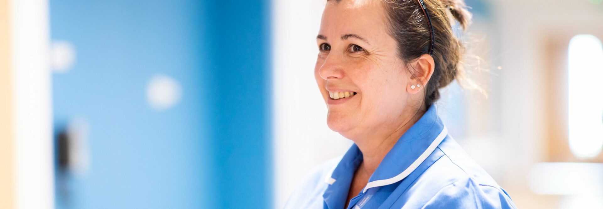 Karen nurse holding folder smiling in corridor