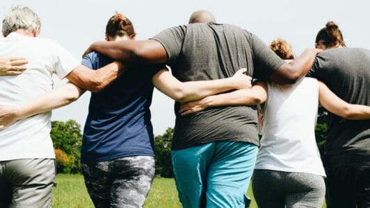 group of people walking along linking arms across their back