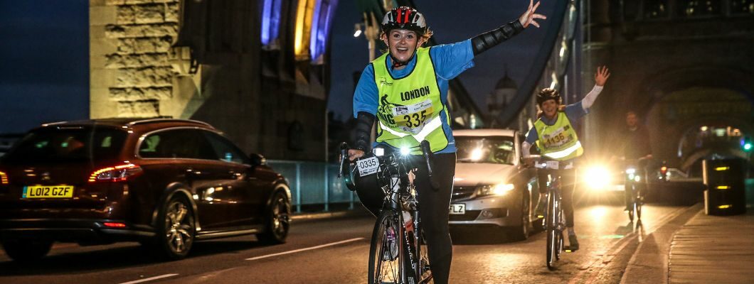 Cyclist taking part in a night ride event, raising their hand in celebration