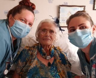 Renee in bed after having make up down with nursing assistants next to her either side