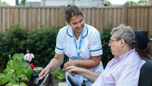 Occupational therapist outside gardening with male patient