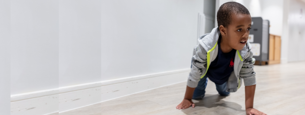 Young boy smiling crawling down corridor at the hospice