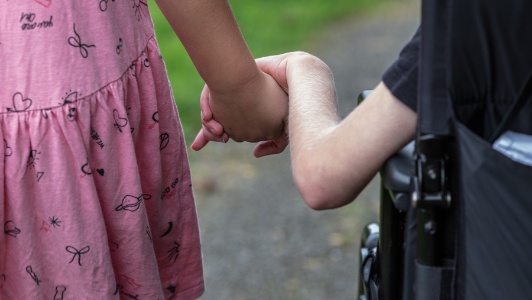 Boy in wheelchair holding hands with sister