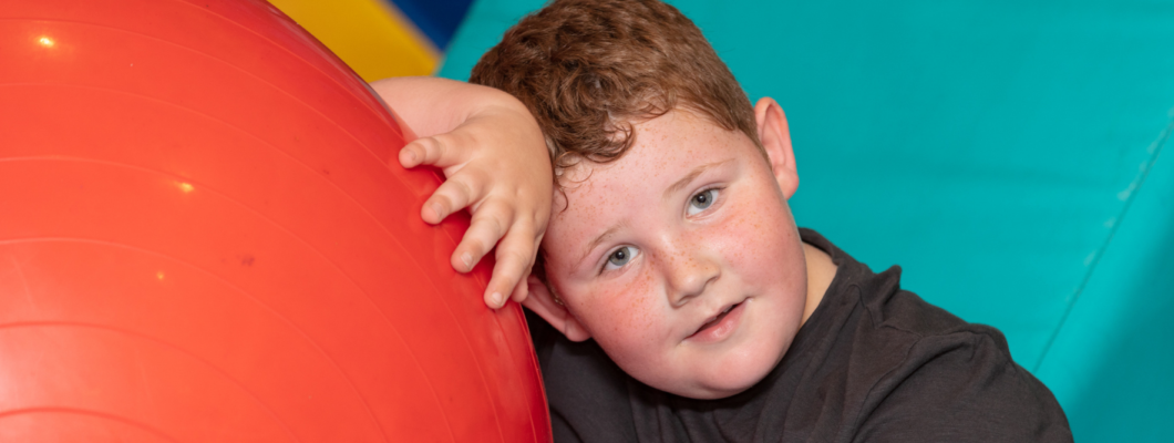 boy looking at camera leaning against soft play