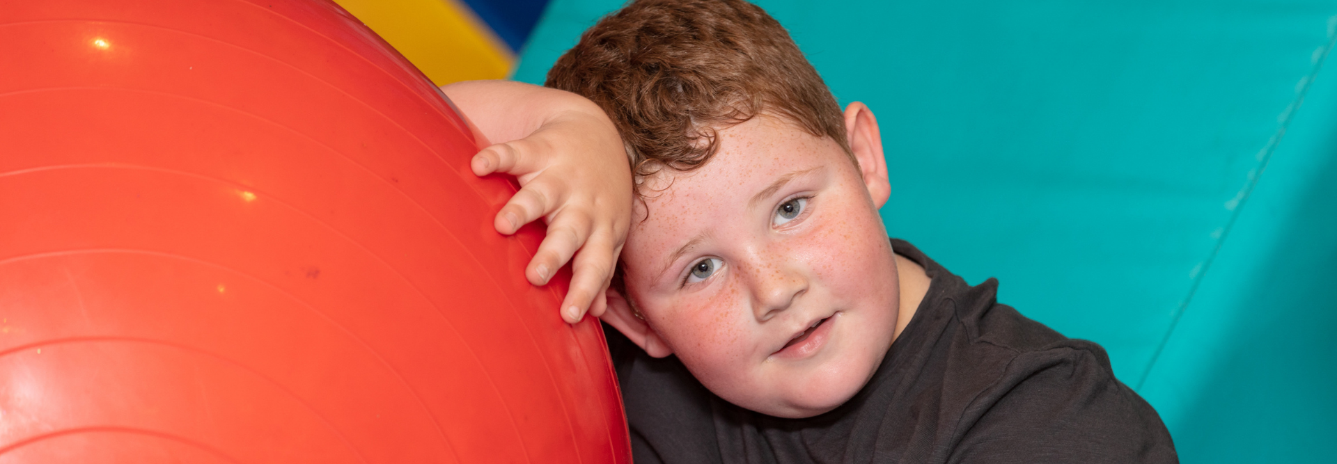 boy looking at camera leaning against soft play