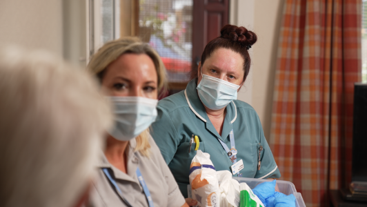 two care team members sat in patient's hospice, in the photo just see backof patient's head