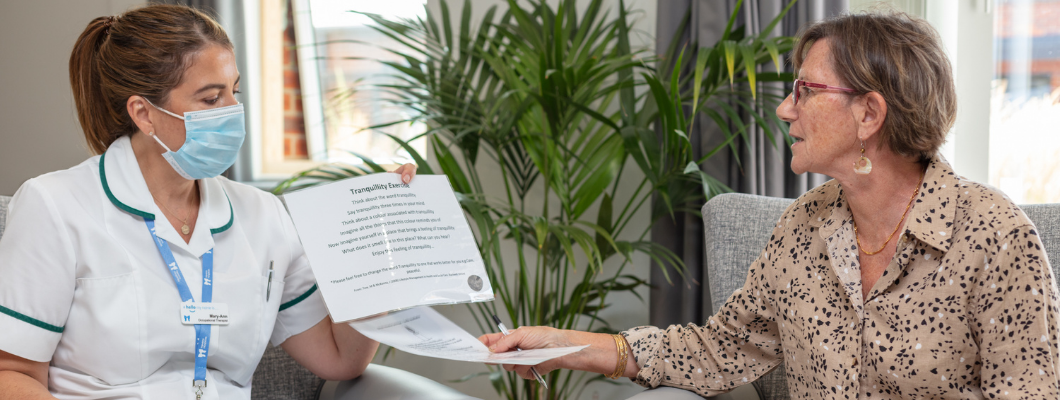 Occupational therapist sat in lounge wearing mask talking to patient