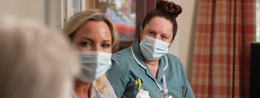 two care team members sat in patient's hospice, in the photo just see backof patient's head