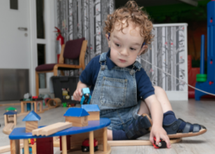 Boy sat on floor playing with wooden toys