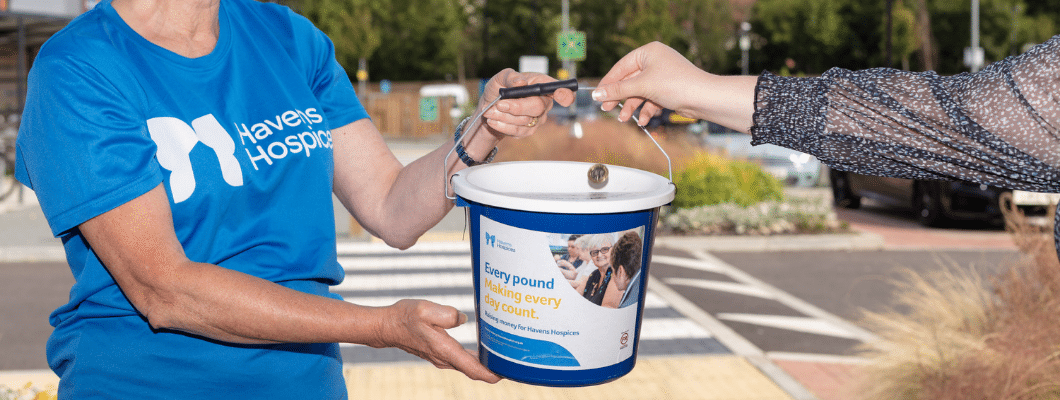 fundraiser wearing blue havens top with hand putting pound into bucket