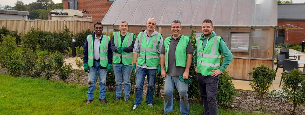 group of men stood outside in garden wearing green hi vis jackets