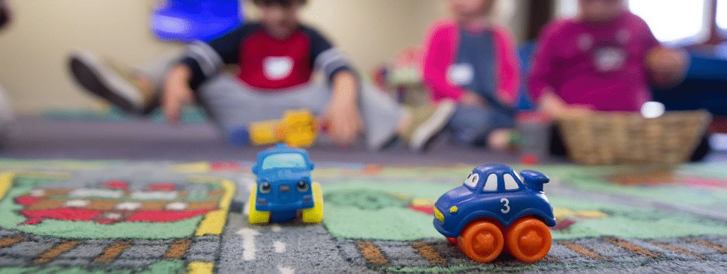 two toy cars on a mat on the floor, in the background can see