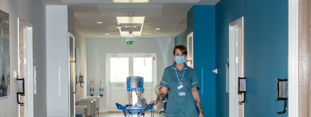 A nurse wearing a face mask walking down the hospice corridor