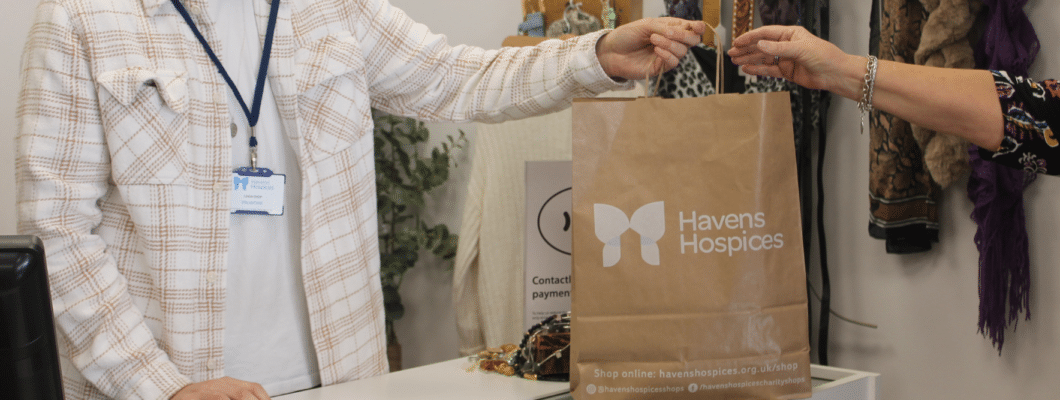 Man in a shop handing over havens brown paper bag