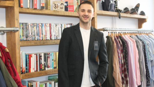 Man in shop modelling jacket stood by bookcase