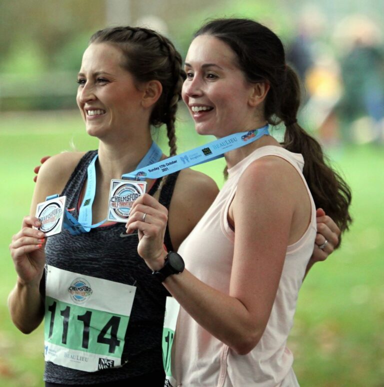 Two female runners holding their medals after completing marathon