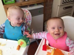 Noah and Ella sat in high chairs next to each other eating