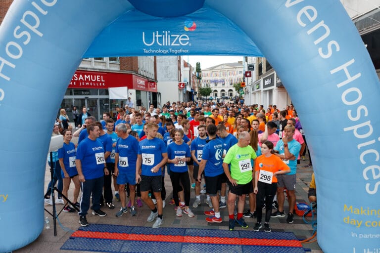 People standing under a Havens Hospices branded arch way at the start of the race