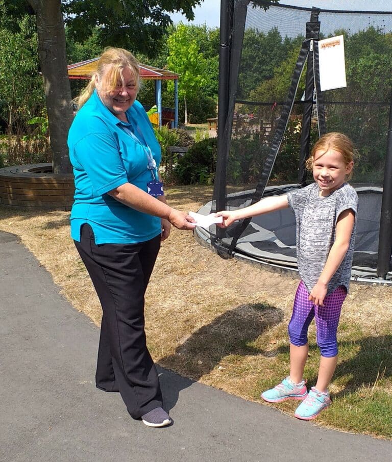 A nurse from Little Havens accepting a cheque donation from Matilda at Little Havens
