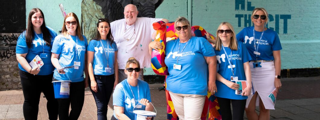 Group of people wearing blue havens tops stood with John bulley artist in Southend by elephant sculpture