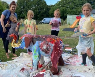 children painting elephant sculpture with adult