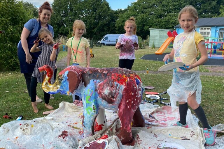 children painting elephant sculpture with adult