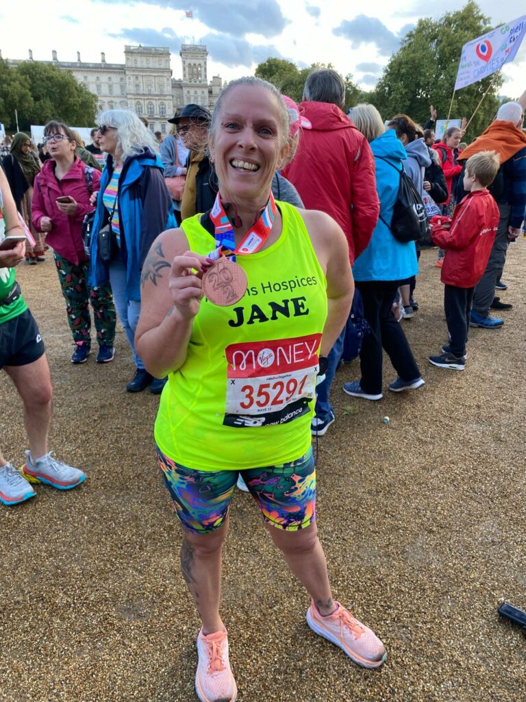 Runner with a Havens Hospices vest holding up her medal