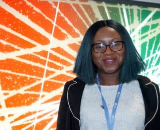 Moorin Babawale standing in front of abstract artwork