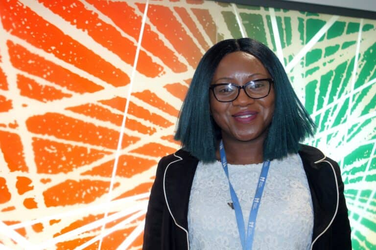 Moorin Babawale standing in front of abstract artwork