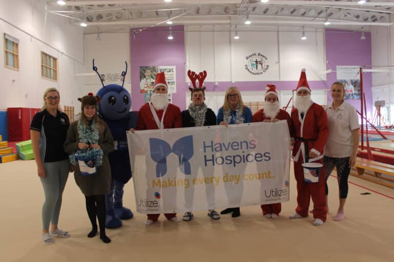 Group of people from South Essex Gymnastics dressed in Santa suits and Betsy the Havens Hospices Mascot