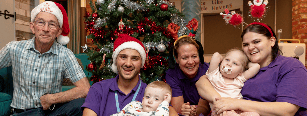 Group of children and carers from Little Havens sat by the Christmas tree