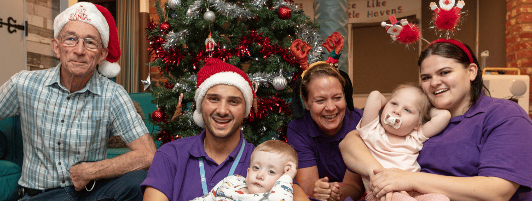 Group of children and carers from Little Havens sat by the Christmas tree