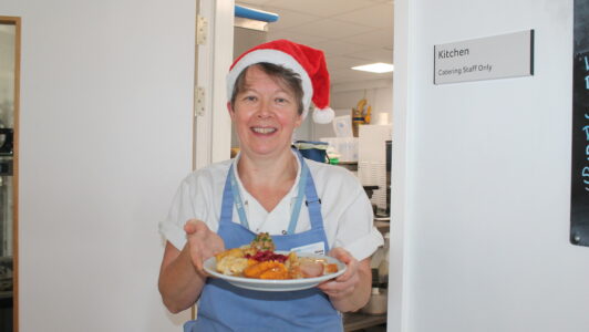 Chef from Fair Havens wearing a santa hat and passing dinner