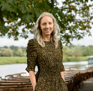 Amy stood outside in a green scenic background smiling at camera