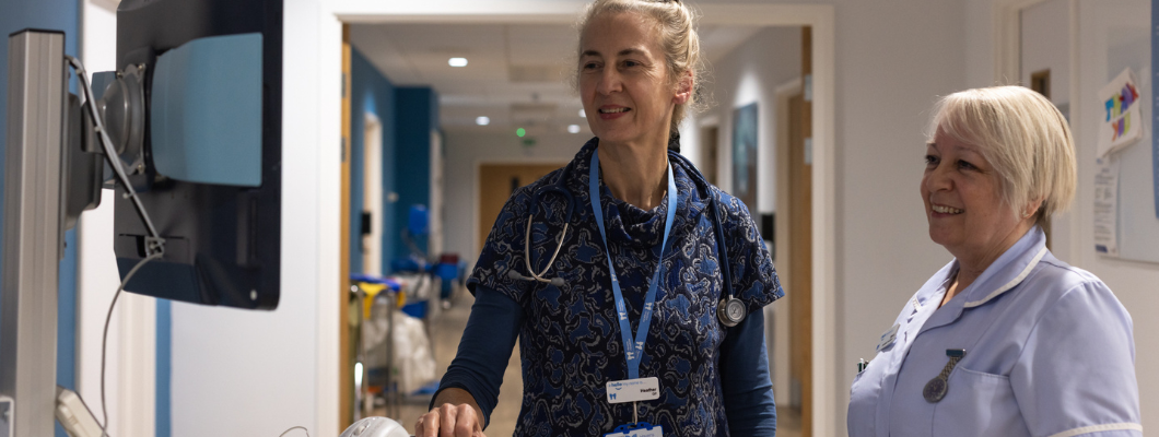 Doctor and nurse stood in corridor at the hospice looking at the screen