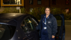 Hospice at Home nursing wearing branded Havens coat stood outside by her car with the car door open