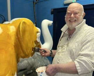 John Bulley, artist, painting elephant sculpture in gold colour